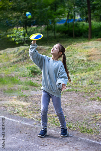 Young girl playing with frisbee in a lush green park environment