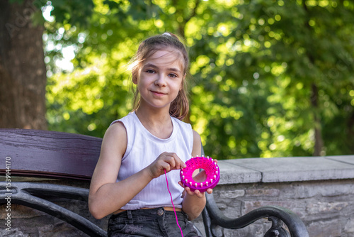 Young girl knitting outdoors on a sunny day in the park