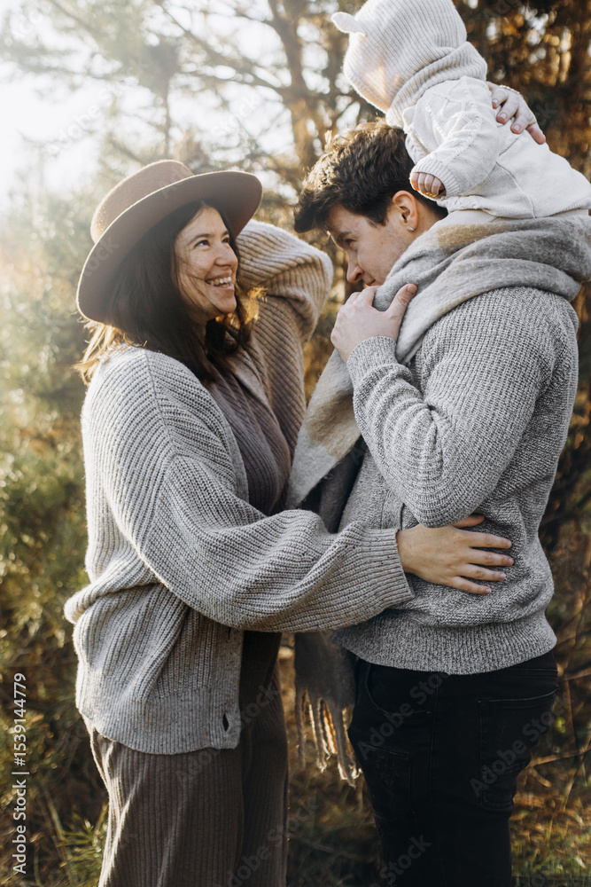 © sonyachny - Happy family hugging with little baby son in autumn field in soft evening light. Parenthood. Mother father and baby in cozy stylish clothes embracing in fall park © sonyachny - Happy family hugging with little baby son in autumn field in soft evening light. Parenthood. Mother father and baby in cozy stylish clothes embracing in fall park