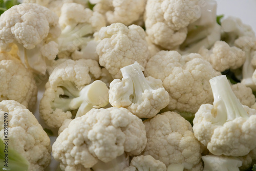 Fresh and raw cauliflower on the white plate.  The cauliflower  -  vegetable is cut into pieces on white background. The vegetable is divided into inflorescences on the plate