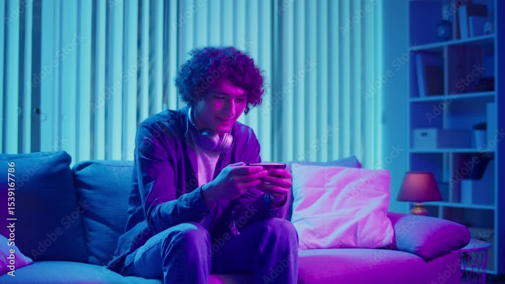 Digital Detox, Mental Health, Focus Mode. Man Relaxes on Sofa Scrolling Phone, Possibly Listening a Podcast or Browsing. Everyday Self-Care and Slow Living in the Digital Age