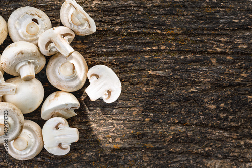 Top view of fresh white mushrooms sliced and whole on rustic dark wooden background with copy space. Organic vegetarian food and cooking ingredient concept
