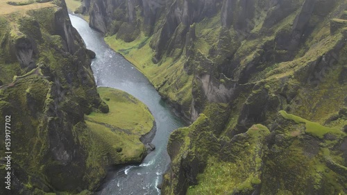 A river flows through a valley with green grass and trees
