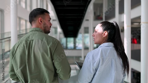 latin American colleagues walking and talking in the hallway of a modern building

