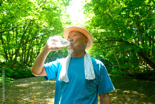 渓流で水分補給をする老人