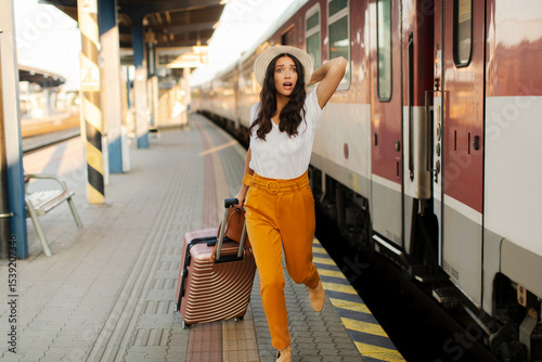Fotografie Woman running and chasing the leaving train at railway station platform, waving