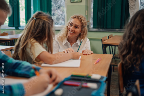 Bild auf Leinwand Teacher helping young girl with her studies in classroom