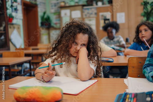 фотографія Bored elementary school student struggling with schoolwork in classroom