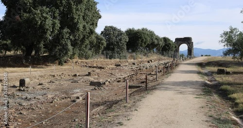 Roman ruins of Caparra with Decumanus Maximus, arch and olive trees.