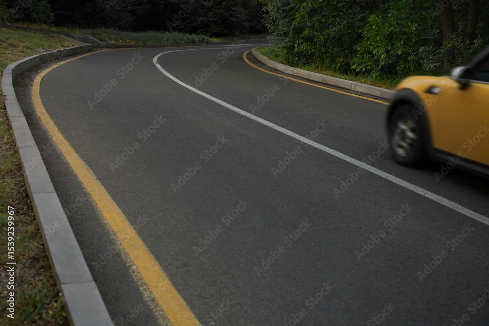 Obraz premium yellow mini car enters a sharp turn during early autumn dusk, emphasizing the importance of careful driving and caution on the road to prevent accidents. fast speedy dangerous moving 