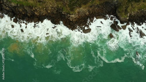 Aerial view of waves crashing against the rocky coastline of zarautz, gipuzkoa, in the basque country during summer