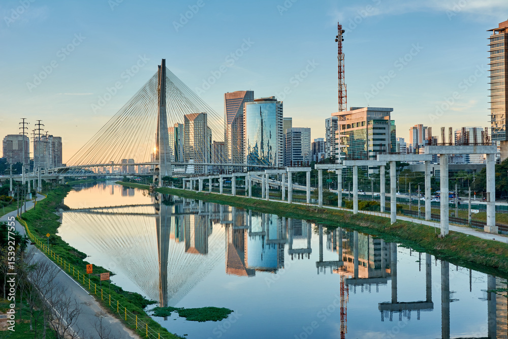 Naklejka premium Urban cityscape with a cable-stayed bridge, modern buildings, and the Pinheiros River in the city of São Paulo.
