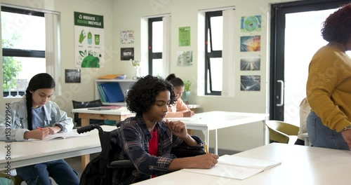 Multiracial students in classroom writing in notebooks, focused and engaged in schoolwork