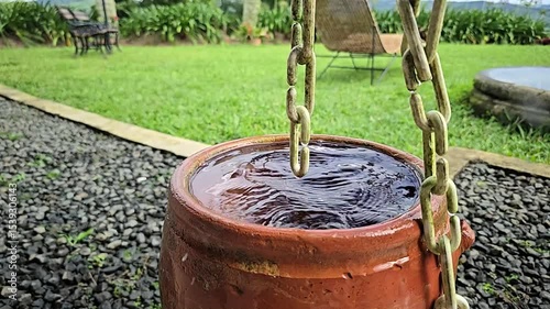 Slow motion of decorative rain chain guiding water from roof to ground, elegant alternative to downspouts, creating cascading waterfall effect, functional and aesthetic in copper under soft rainfall