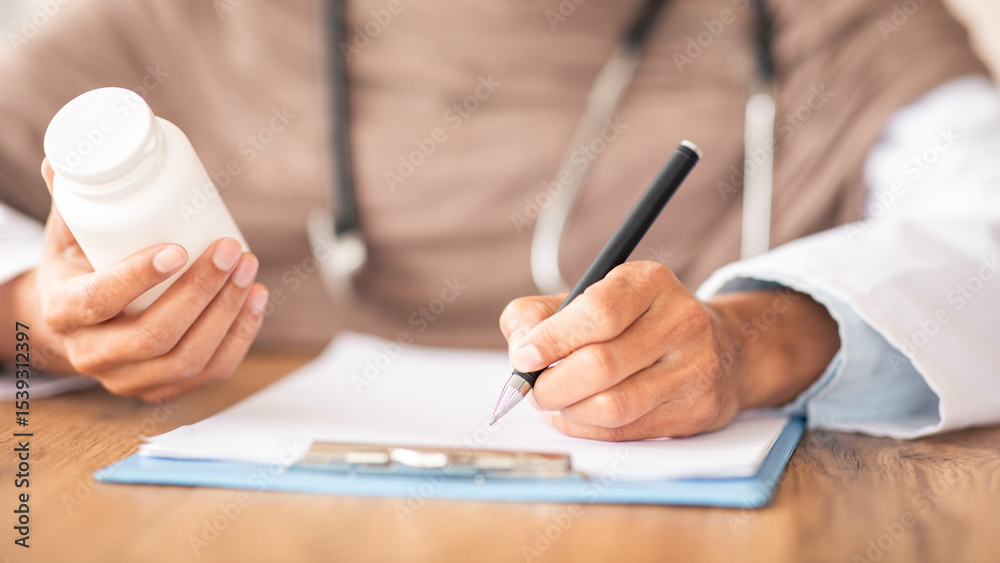 Fototapeta premium Medicine, pills, vitamins concept. Closeup of unrecognizable female doctor in hijab holding medicine, writing prescription in medical chart, prescribing treatment for patient in hospital, cropped