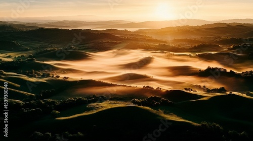 Sunrise over rolling hills shrouded in morning mist. Lush valleys bathed in golden light