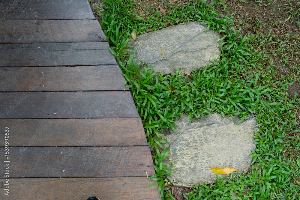 Obraz premium Wooden deck meets stone path in lush garden setting, creating natural and serene atmosphere