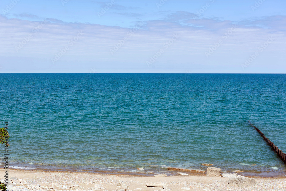 Fototapeta premium Serene lake shore with blue water and horizon under clear sky