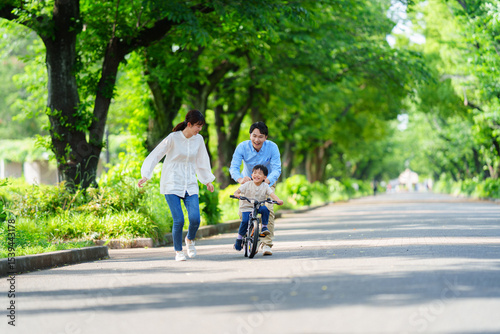 両親と自転車の練習をする5歳の少年