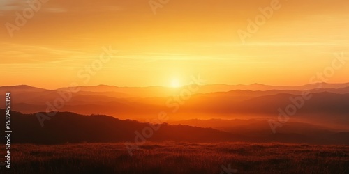 Vibrant orange sunrise over rolling hills and distant mountain ranges with a peaceful and warm atmosphere