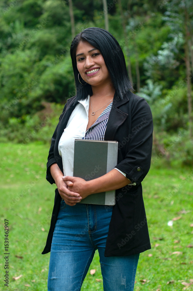 Fototapeta premium Smiling south american teacher holding a book in a green park