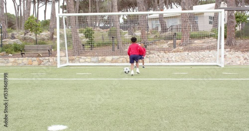 Multiracial boys playing soccer, scoring goal on field, celebrating teamwork and success