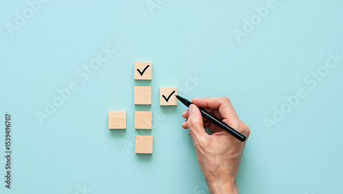 Hand Marking a Checklist with Checkmark Boxes on Wooden Blocks Arranged in a Creative Pattern on a Blue Background, Representing Productivity and Task Progress
