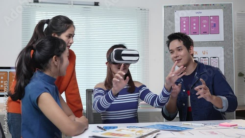 Professional UI and UX designers collaborating while testing virtual reality headset, exploring innovative design solutions in modern office workspace with excitement and creativity