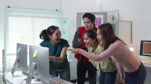 Programmers are having fun, celebrating success of their project in modern office, looking at computer screen, pointing, high fiving each other