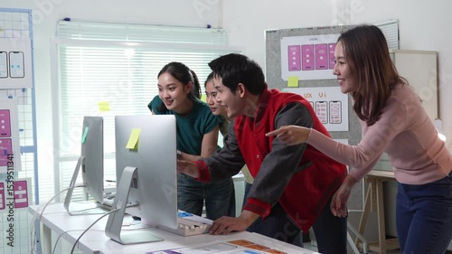 Professional design team celebrating successful project completion, expressing shared excitement and joy while gathered around computer in modern office workspace