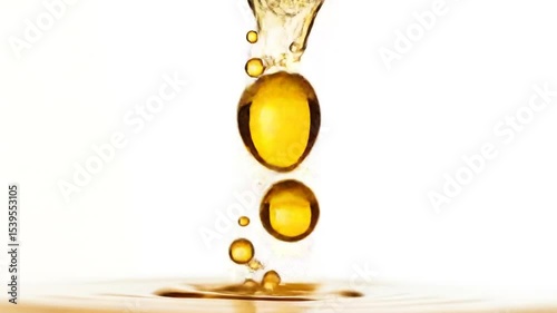 Golden Viscous Liquid Droplets Gracefully Descend Creating Captivating Ripples On A White Surface