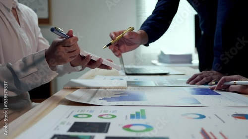 Corporate team members analyzing financial data, collaborating on growth strategies through detailed chart review and strategic discussion in professional office setting