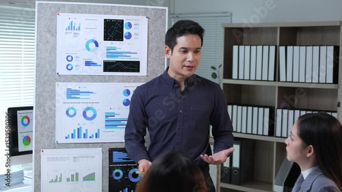 Competent asian businessman manager presenting company marketing data analysis information to colleagues in meeting room, explaining charts and graphs showing company growth and success