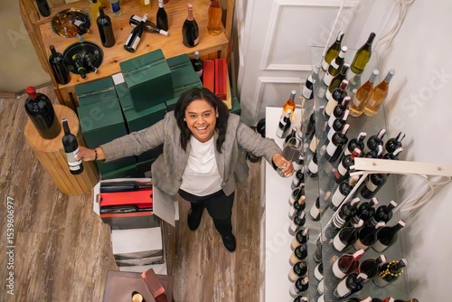 Wine store owner holding wine bottle and glass, smiling at camera