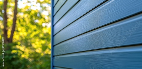 Blue siding on a house with blurred trees in the background