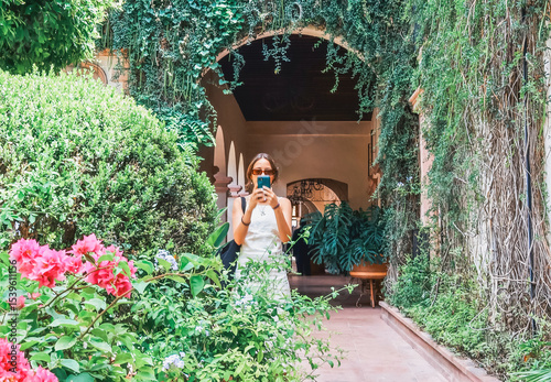 Blurred Young travel blogger taking photos in a lush green courtyard
