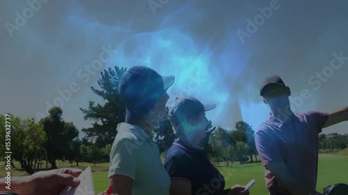 Senior golfer noting yardage on pad while partners leaning pointing down fairway planning golf shot