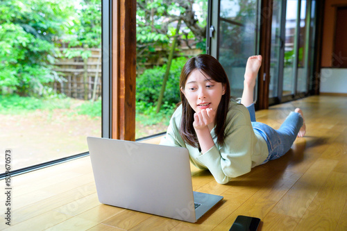 快適な空間でうつ伏せになりノートパソコンを操作する女性のリモートワークライフ Free Download 快適な空間でうつ伏せになりノートパソコンを操作する女性のリモートワークライフ - GFXLoad