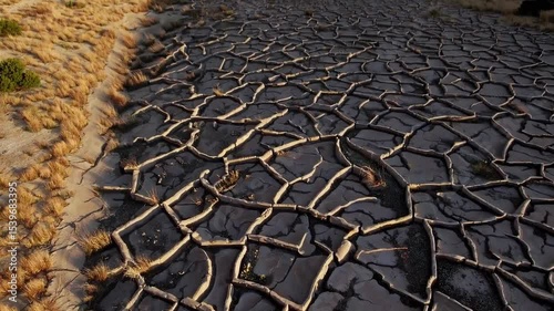 Dry Reservoir with Cracked Ground and Sparse Vegetation Under Clear Sky on a Bright Sunny Day
