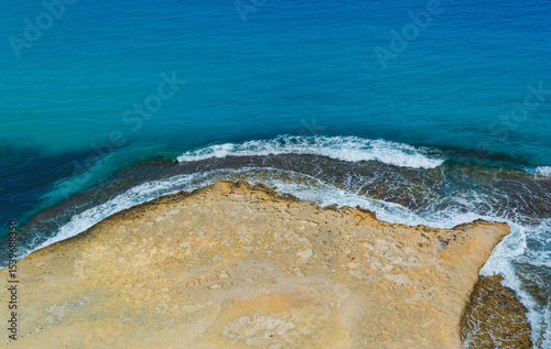 top view of Coastline with yellow sand meeting blue water