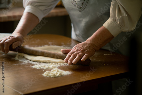 Old woman rolling dough on a table