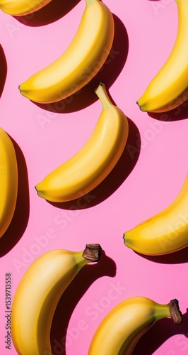 Fresh yellow bananas arranged on a bright pink background create a vibrant and playful mood for any design