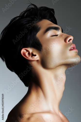 Male model showcasing a striking profile with deep expressions against a neutral background in a studio setting