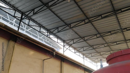 Spacious industrial warehouse interior featuring a metal roof structure with light, walls, and equipment visible.