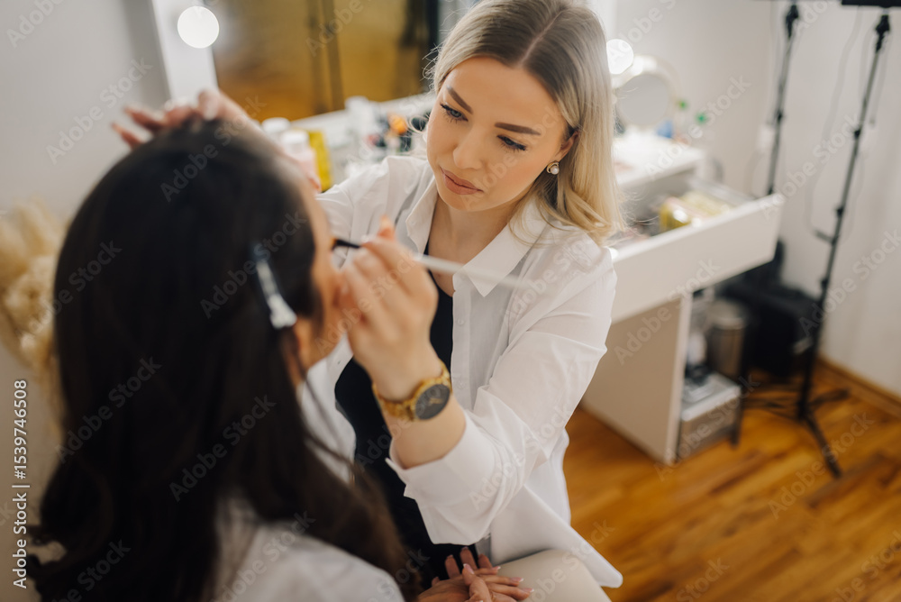 Professional makeup artist applying makeup on client's face in beauty salon Professional makeup artist applying makeup on client's face in beauty salon