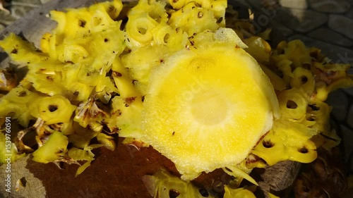 A scene showing a freshly peeled pineapple on a wooden cutting board, showcasing the pineapple's bright yellow core and textured skin. 