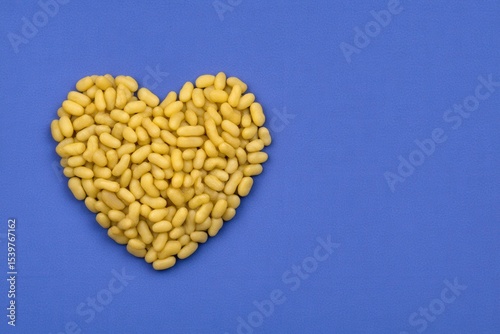 Heart shape made from yellow candies on a contrasting blue background creating a playful and cheerful composition that embodies joy and affection while adding a vibrant touch to any creative