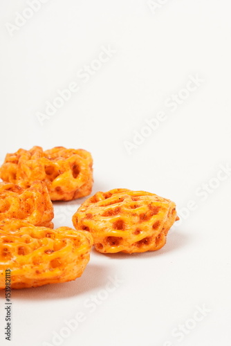 A pile of spicy Indonesian crackers or Kerupuk with spiral twists, coated in red-orange chili powder and rich spices. Bold, flavorful, and appetite-boosting. Photographed against a white background.