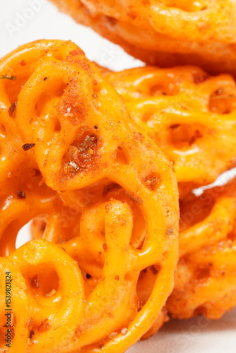 A pile of spicy Indonesian crackers or Kerupuk with spiral twists, coated in red-orange chili powder and rich spices. Bold, flavorful, and appetite-boosting. Photographed against a white background.