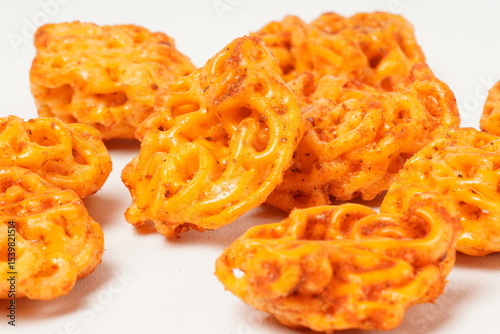 A pile of spicy Indonesian crackers or Kerupuk with spiral twists, coated in red-orange chili powder and rich spices. Bold, flavorful, and appetite-boosting. Photographed against a white background.